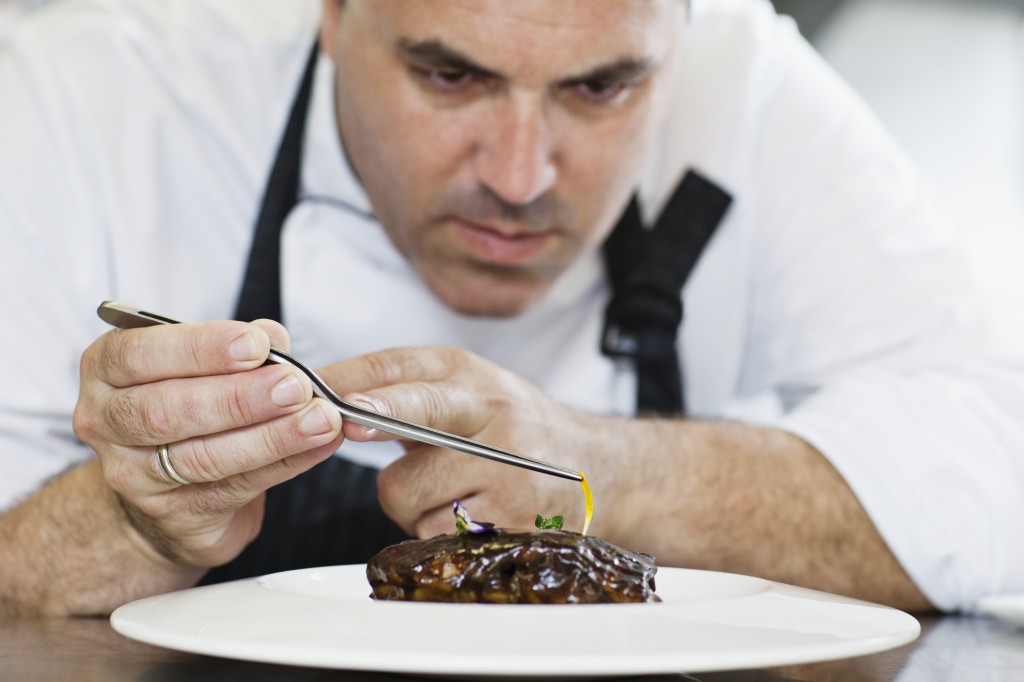 Male chef preparing meal on plate